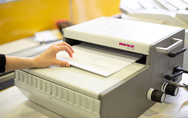 Conseillère fermant une reliure métallique à l'agence COPYTOP Saint Philippe du Roule à Paris