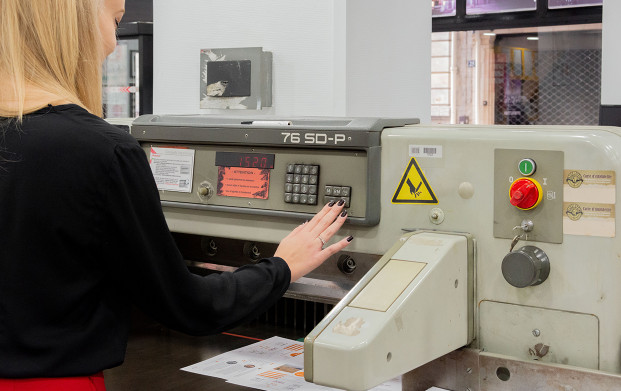 Conseillère utilisant le massicot de l'agence COPYTOP Mogador - Trinité à Paris