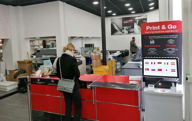 Intérieur de l'agence COPYTOP Champs Elysées à Paris avec la borne photo et le comptoir