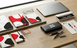 Décor de bureau présentant une gamme complète de papeterie de bureau personnalisée : carnets, blocs-notes, papier à en-tête, enveloppes, chemises, sous-mains et autres fournitures imprimées aux couleurs de l'entreprise.