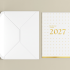 Découvrez les cartes de vœux avec finitions premium: pelliculage, dorure, vernis sélectif, vernis 3D. Gros plan sur une carte de vœux d'entreprise premium au format A5, imprimée sur papier rigide certifié FSC® avec un logo brillant en dorure or sur une base finitions pelliculage peau de pêche.
