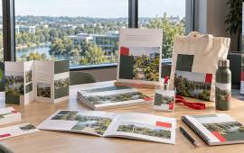 Cartes, dépliants, brochures, dossier relié, badge et sac personnalisé dans un bureau donnant sur un parc d’activités de Cergy-Pontoise.